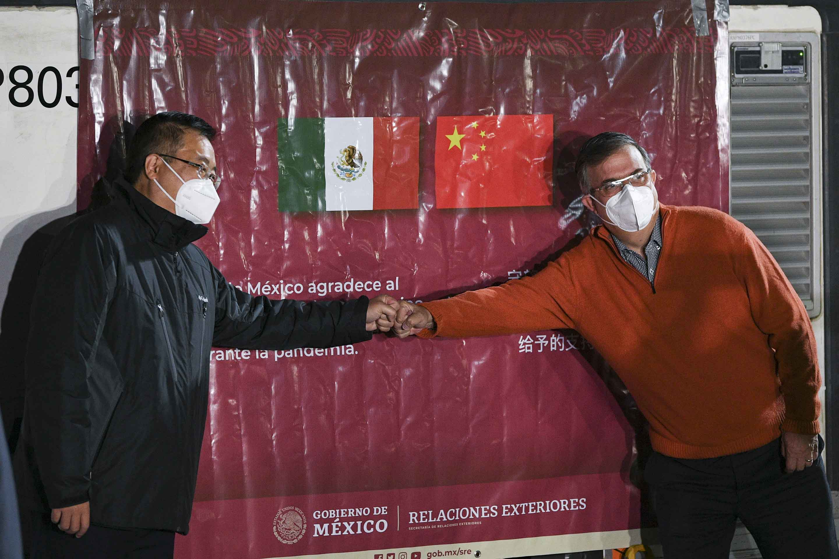 メキシコのマルセロ・エブラルド外相（右）と祝青橋駐メキシコ中国大使（左）は拳をぶつけ合い、メキシコに届いたシノバック製ワクチンのコンテナを歓迎した（2021年2月27日）